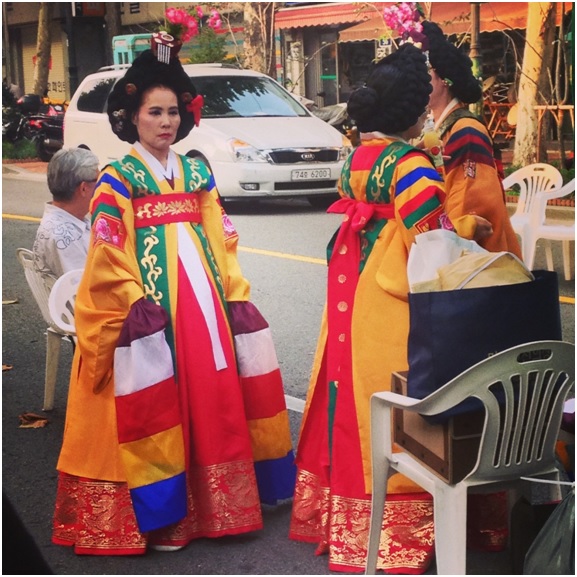 Seul’de bir sokak festivali, ve sıralarını bekleyen yerel kıyafetli kadınlar
